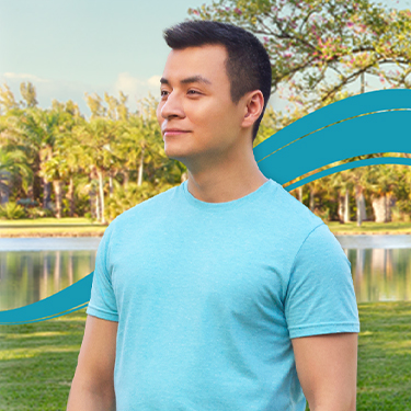 Hypothetical patient with anemia in beta-thalassemia (BT) in an aqua shirt outside near a lake in front of a tree with few leaves